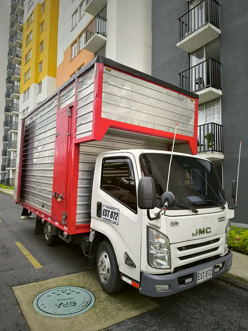 Furgón con detalles rojos estacionado frente a un edificio